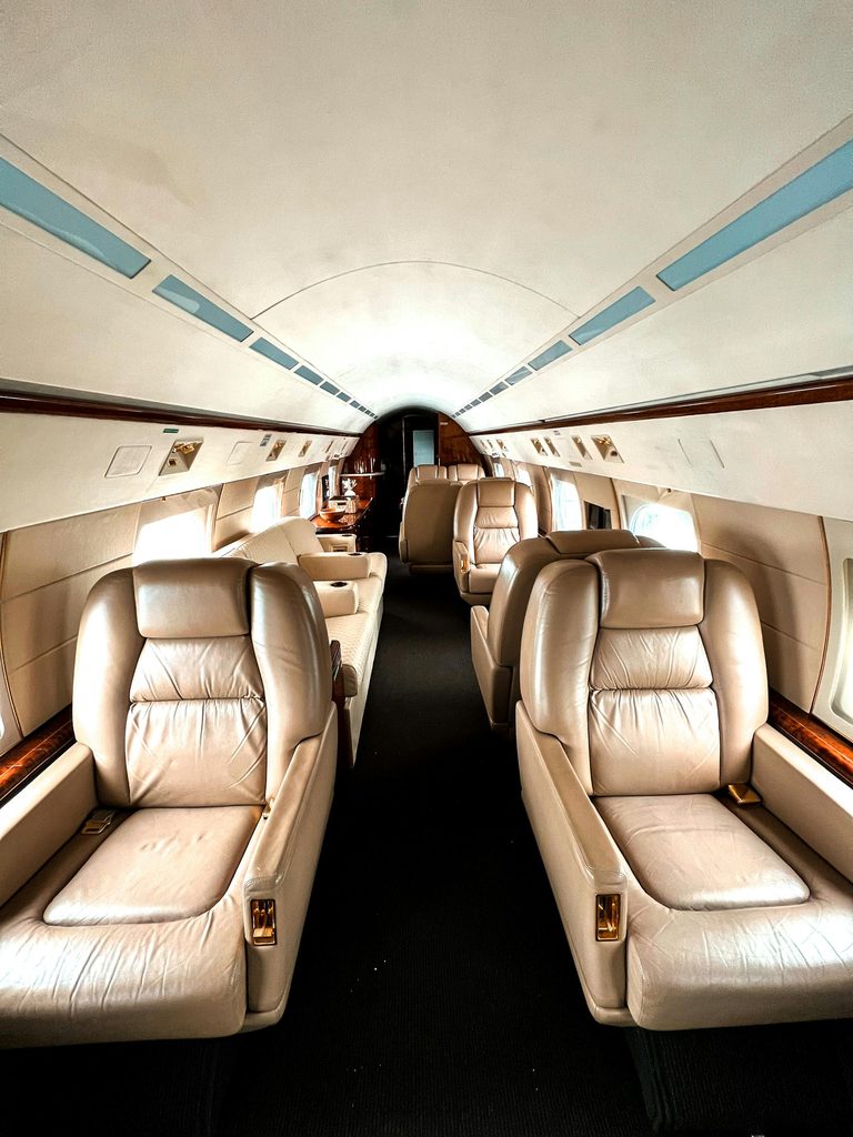 The cabin of a private jet, leather seats along the aisle.